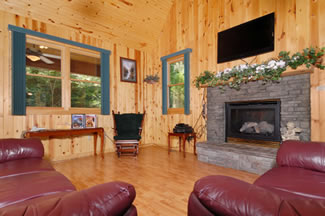 Leather couches that have face a flat screen tv that is hung above a stone gas fireplace.